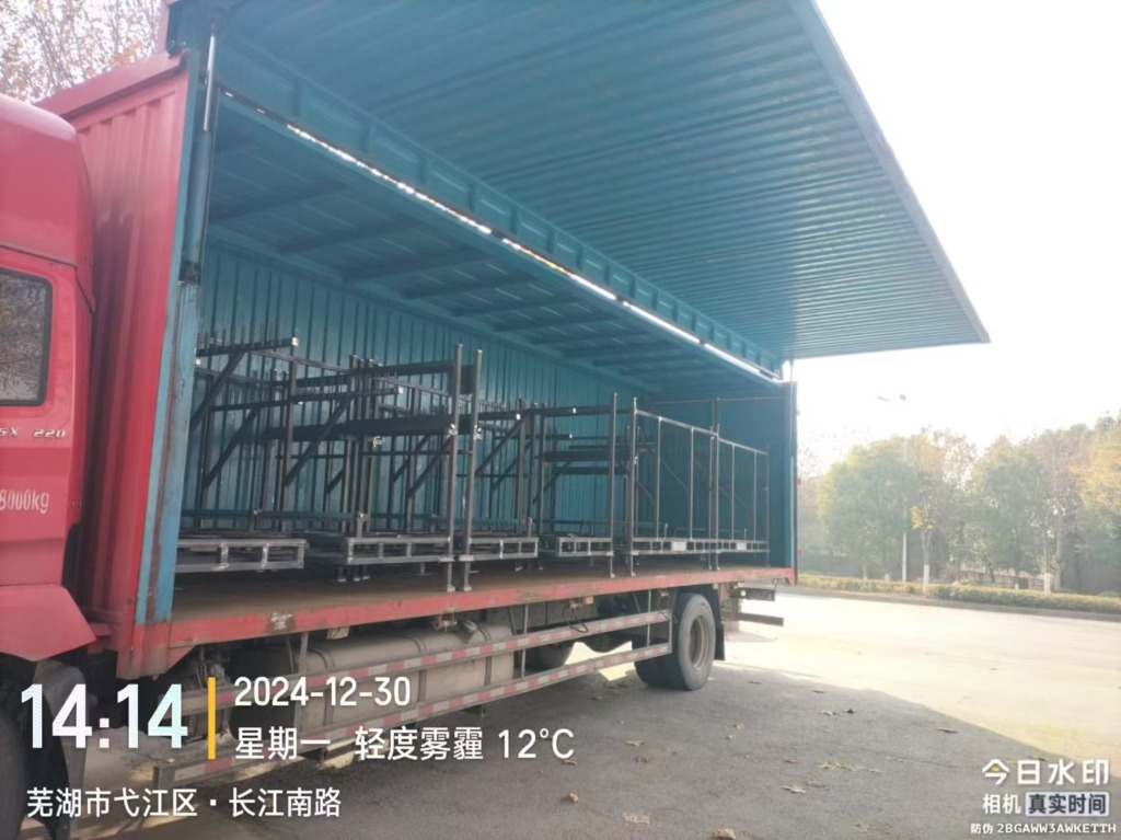 Fully welded black turnover racks loaded onto a flatbed trailer truck for customer delivery from the factory